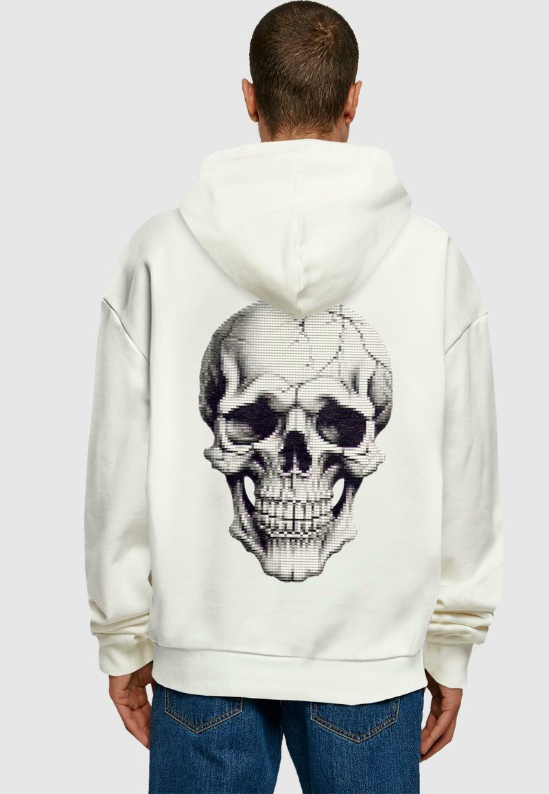 White hoodie featuring a large, graphic black and gray skull design on the back. Soft material with a loose fit and kangaroo pocket.