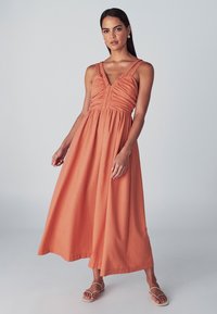 Terrakotavärvi maksikleit volditud ülakehaosaga, V-kaelusega ja kahekordsete õlapaeladega; kerge kangaga voolava siluetiga.