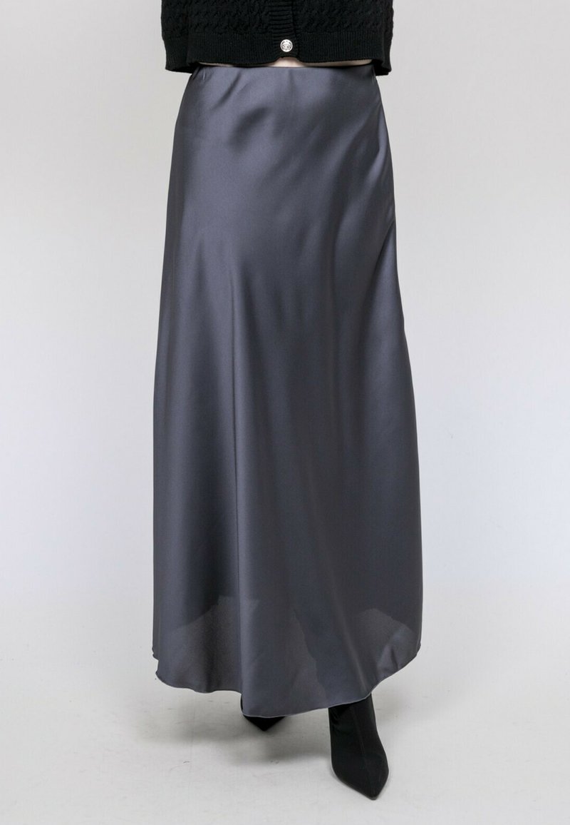 Jupe maxi en satin gris avec une texture lisse, coupe évasée, éclat subtil et taille haute, associée à des bottines noires.