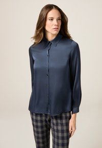 Blusa in satin blu navy con colletto classico, chiusura a bottoni e maniche lunghe. Presenta una texture liscia e una leggera lucentezza.