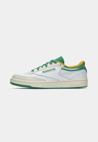 Biele tenisky s akcentmi v zelenej a žltej farbe, hladký kožený zvršok, zaoblená špička, plochá podošva a logo Reebok na boku.