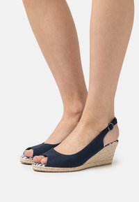 Chaussures à talons compensés bleu marine avec un design à bout ouvert, fabriquées en tissu avec une finition texturée, dotées d'une bride de cheville réglable et d'une semelle en jute tissée.