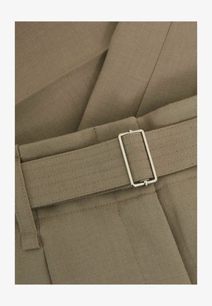 Világosbarna nadrág texturált anyagból, keskeny övvel és ezüst szögletes csattal, tiszta varrási részletekkel kiemelve.