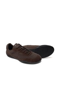 Paire de chaussures décontractées marron foncé à lacets avec semelles noires texturées, une chaussure vue de côté et l’autre vue de la semelle.