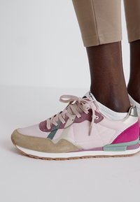 Baskets rose clair avec des accents en daim et en maille verts, violets et beiges. Comprend des lacets ronds et un col rembourré avec un détail de logo.