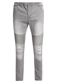 Jeans de mezclilla gris con corte ajustado, que presentan acentos acanalados en las rodillas, detalles desgastados y un cierre de botón.
