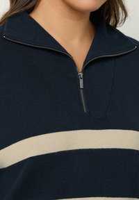 Pullover a righe navy e beige con collo a mezza zip, caratterizzato da una texture a coste e una vestibilità moderna.