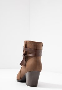 Brązowe zamszowe botki za kostkę z brązowym skórzanym paskiem i detalem w postaci kokardy, z piętką nałożoną i gładką powierzchnią.