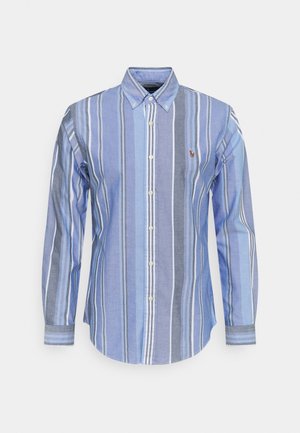 Chemise à manches longues boutonnée avec des rayures verticales bleues, grises et blanches et un petit logo brodé sur la poitrine gauche.