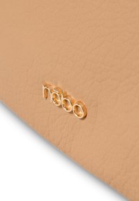 Borsa in finta pelle beige con una superficie texture sottile, con un logo metallico dorato che reca la scritta "nobo" ben visibile.