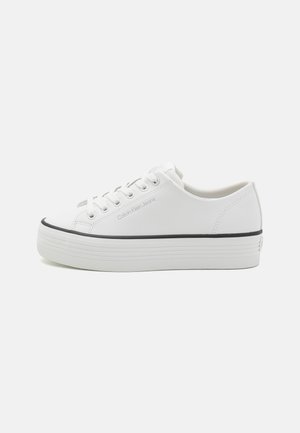 Biały niski sneakers z grubą podeszwą, z przodu na sznurówki oraz logo "Calvin Klein Jeans" po boku, przedstawiony na jednolitym tle.