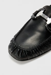 Sorte skinn loafers med rund tå, plisserte detaljer og en sølvfarget hardware aksent med navnet "KARL" graverte.