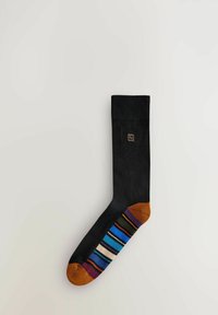 Calzino nero con parte superiore testurizzata, punta arancione e strisce multicolori a motivi sul lato. Presenta un piccolo logo vicino al bordo.