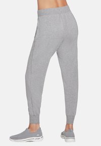 Gray jogger pants with a ribbed waistband and elastic cuffs, featuring side pockets and a soft, textured fabric finish.