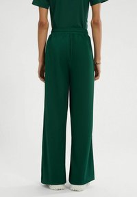 Groene wijde broeken van een gestructureerde, lichte stof. Elastische tailleband en een losse pasvorm voor comfort. Geen zichtbare patronen of accenten.