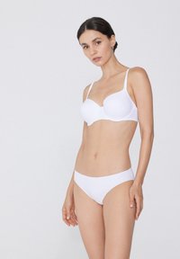 Weißer BH und passende Bikini-Briefs, beide nahtlos mit glatter Struktur. Verstellbare Träger am BH verbessern Passform und Komfort.