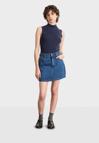 Mörkblå ärmlös ribbad topp i kombination med en blå denim A-linjeformad kjol. Outfitten inkluderar grå strumpor och svarta loafers. Enkelt, avslappnat stil.
