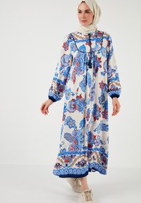 Rochie lungă cu model floral în crem, cu desene albastre și roșii. Prezintă mâneci bufante, gât rotund și o margine cu accente albastre.