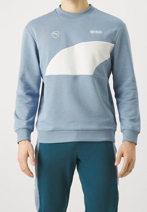 Felpa azzurra chiaro realizzata in tessuto misto cotone, con un pannello curvo bianco, polsini a costine e un collo rotondo. Include dettagli del logo.