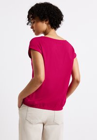 Fuchsie krátký rukáv blůza s volným střihem a elastickým lemem, vyrobená z hladkého materiálu. Má široký výstřih a jednobarevný design.