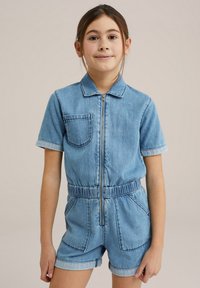 Denim kratek kombinezon s kratkimi rokavi, sprednjim zadrgo, ovratnikom in elastičnim pasom. Ima žep na prsih in stranske žepe. Svetlo modra barva.