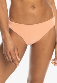 Hladké bikiny s rebrovaným vzorom v jemne broskyňovej farbe s nízkym pásom. Hladká textúra a minimalistický dizajn, vhodné na kombinovanie s inými kúskami.