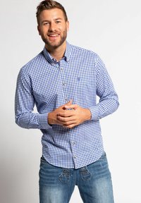 Karierter Button-Up-Shirt in Blau- und Weißtönen mit langen Ärmeln, Brusttasche und goldenen Knöpfen, kombiniert mit hellblauen Jeans.
