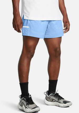 Lyseblå træningsshorts med kontrasterende hvid syning og sidelomme; båret med sorte sokker og multitonede sneakers.