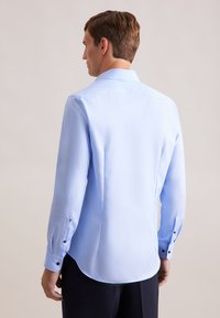 Lichtblauwe langemouwen shirt van een gladde stof, met een klassieke kraag, knopenmanchetten en een afgeronde zoom. Subtiele stikdetails zichtbaar.