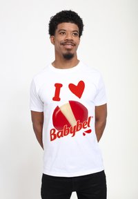 Bílý bavlněný tričko s červenou grafikou s textem "I ♥ Babybel" a ilustrací segmentovaného sýrového kola Babybel.