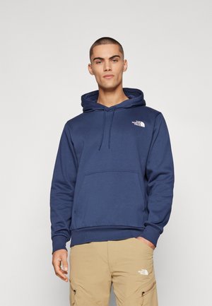 Felpa con cappuccio di colore blu navy, dotata di tasca frontale, cappuccio con lacci e logo bianco sul lato sinistro del petto. Materiale in cotone con una texture morbida.