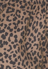 Látka s leopardím potiskem v odstínech hnědé a černé, s jemným, texturovaným povrchem a nepravidelnými skvrnami různých velikostí.