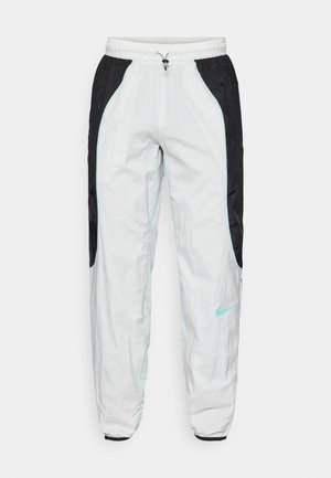 Witte en zwarte sportbroek met elastische tailleband en trekkoord, voorzien van lichtblauwe accenten en zijzakken. Gemaakt van lichtgewicht materiaal.