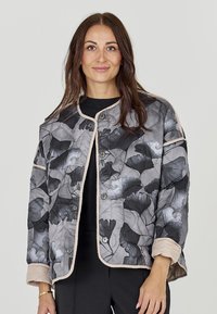 Gewatteerd jack in zwart en grijs met bloemmotieven, voorzien van beige biezen en drukknoopsluiting. Lange mouwen met opgerolde manchetten.