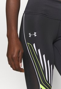 Svarta atletiska leggings har en meshpanel och djärva accentfärger i vitt och neongrönt, med en silverfärgad logotyp på låret.