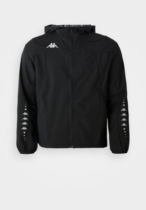 Black lightweight jacket made of nylon with a zip front, hood, and elastic cuffs. Features a logo on the chest and patterned accents on the sleeves.