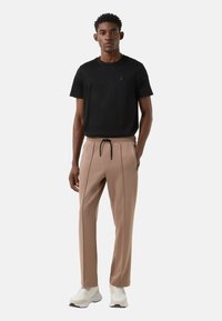 Zwart T-shirt met korte mouwen en een ronde hals, gecombineerd met beige taps toelopende broek met zijzakken en een taille met trekkoord.