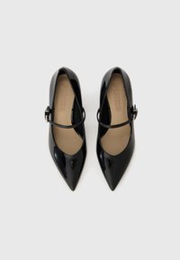 Escarpins en cuir verni noir avec des bouts pointus, dotés d'une seule lanière à la cheville et d'une semelle intérieure beige gravée du nom de la marque "PINKO."