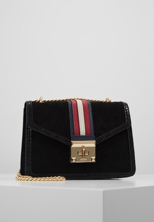 Sac à main en daim noir avec une bandoulière en chaîne dorée, un fermoir doré et des rayures verticales rouges, blanches et bleues sur le rabat avant.