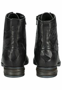 Bottines en cuir noir avec une finition texturée, fermetures éclair sur les côtés et un talon empilé. Coutures visibles à l'arrière.