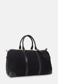 Schwarze Reisetasche mit schwarzen Lederelementen, runder Form, doppelten Griffen, goldenen Beschlägen und einem Luggage-Tag-Detail. Weiche Textur.