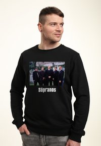 Černá mikina s potiskem šesti postav v oblecích na hřbitově a textem "The Sopranos" pod obrázkem.