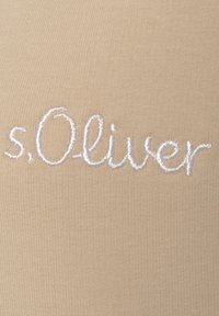 Beige fabric with a ribbed texture featuring white embroidered text reading "s.Oliver" in a cursive font. Quality stitching detail is visible.