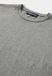 Szary sweter z okrągłym dekoltem wykonany z miękkiej bawełny, o gładkiej fakturze i klasycznym kroju, z ciemnoniebieską metką na dekolcie.