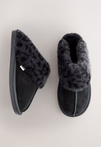 Chaussons en daim noir avec un col en fausse fourrure noire douce orné d'un imprimé léopard, semelle plate en caoutchouc et détail de couture contrastante.
