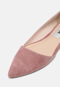 Chaussure plate pour femme à bout pointu en daim rose poussiéreux avec doublure intérieure beige sur fond blanc.