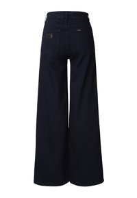 Tmavomodré džínsy so širokými nohavicami a vysokým pásom, s koženou nášivkou na zadnej strane a dvoma zadnými vreckami. Vyrobené z rifľoviny.