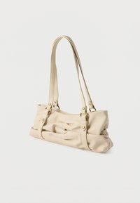 Sac à bandoulière en cuir souple beige avec détails froncés, double bandoulière et quincaillerie dorée sur fond blanc.