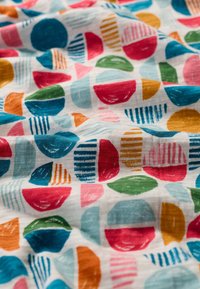 Cotton fabric featuring a colorful geometric pattern with circles and semi-circles in blue, pink, green, yellow, and orange on a white background.