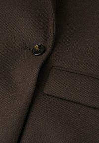 Brown wool blazer with a textured surface, featuring a black button and a neatly structured lapel and pocket.